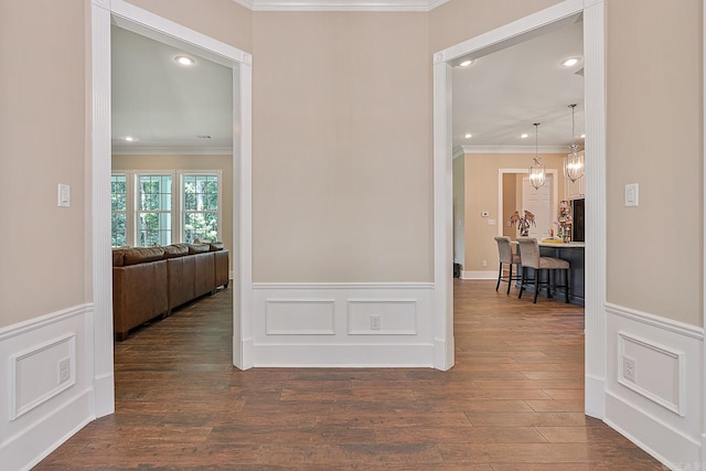 corridor featuring a notable chandelier, dark hardwood / wood-style flooring, and ornamental molding