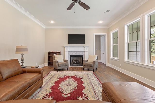 living room with a high end fireplace, crown molding, dark hardwood / wood-style floors, and ceiling fan