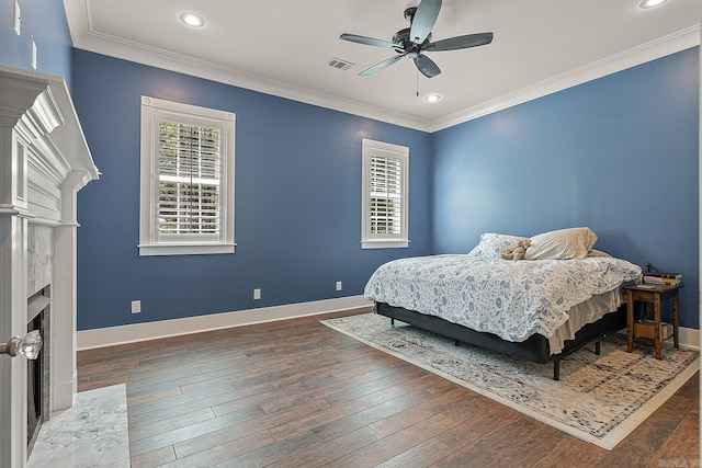 bedroom with dark wood-type flooring, ceiling fan, crown molding, and a high end fireplace