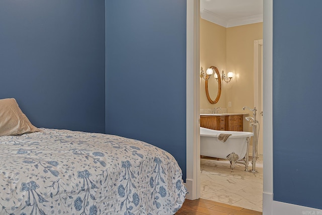 bedroom featuring crown molding, hardwood / wood-style floors, sink, and ensuite bathroom