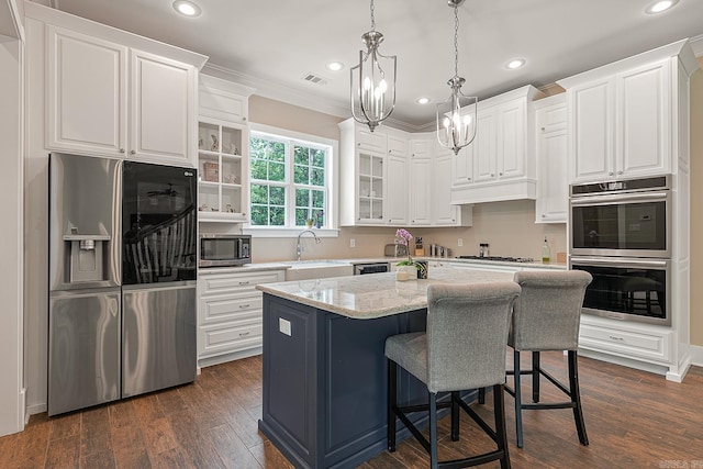 kitchen with appliances with stainless steel finishes, white cabinetry, a kitchen island, and dark wood-type flooring