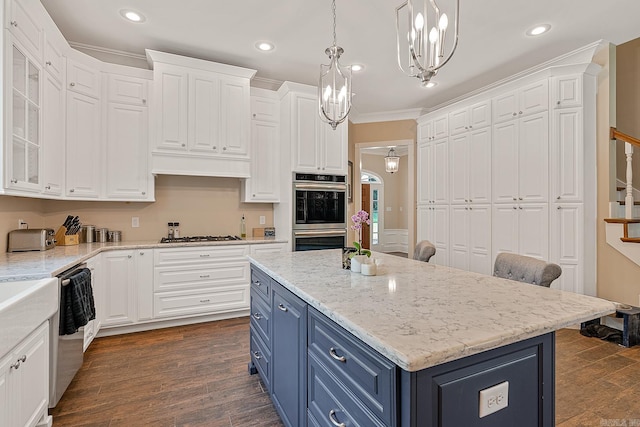 kitchen with stainless steel appliances, white cabinets, hanging light fixtures, dark hardwood / wood-style floors, and blue cabinetry