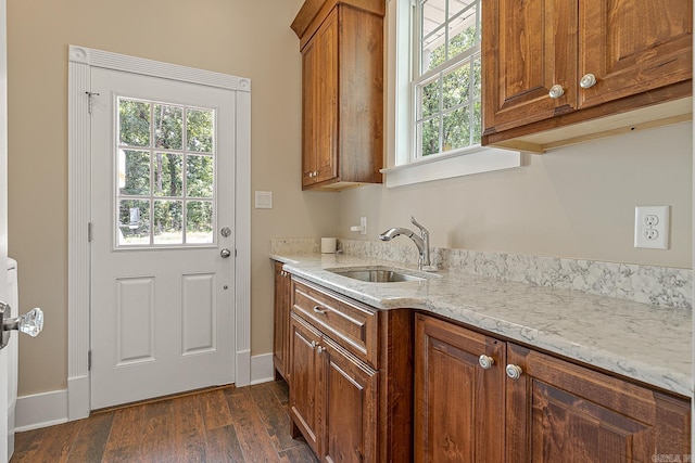 kitchen with light stone countertops, dark hardwood / wood-style flooring, and sink