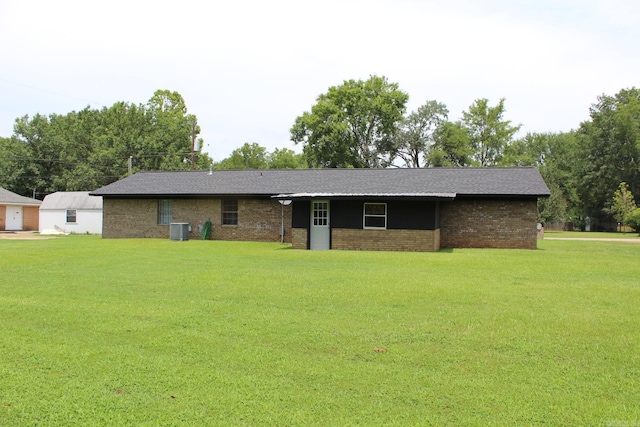 ranch-style home featuring cooling unit, a front lawn, and brick siding