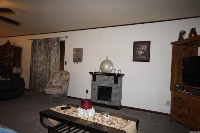 carpeted living room featuring a stone fireplace and ceiling fan