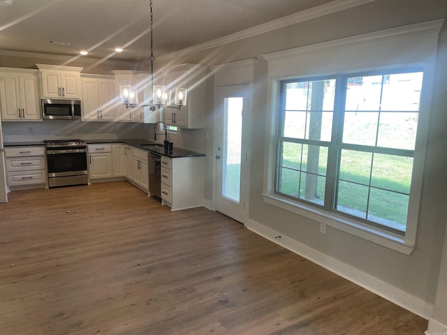 kitchen featuring white cabinetry, appliances with stainless steel finishes, decorative light fixtures, and backsplash