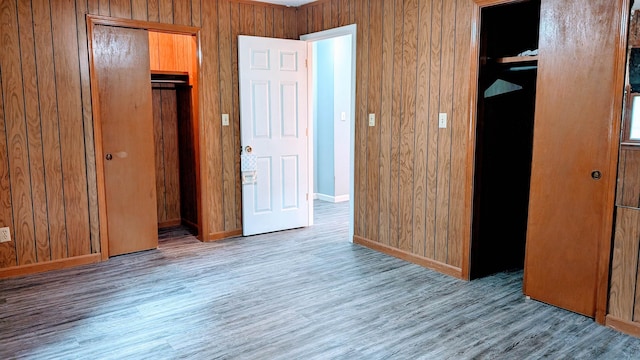 unfurnished bedroom featuring wood walls, a closet, and wood-type flooring