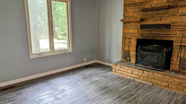 unfurnished living room with a wood stove, wooden walls, and dark wood-type flooring