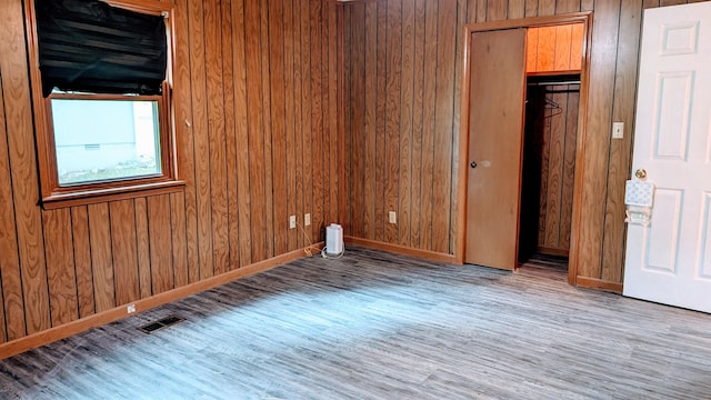 spare room featuring wood walls and wood-type flooring