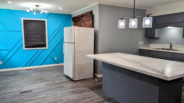 kitchen featuring white fridge, a center island, dark hardwood / wood-style flooring, hanging light fixtures, and sink