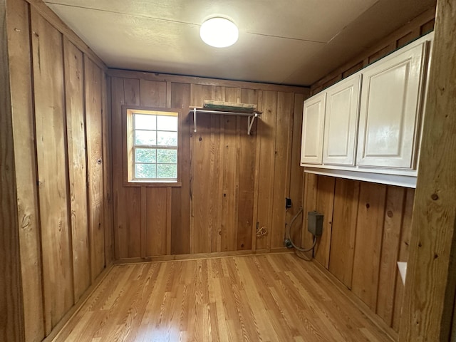 washroom with cabinets, wood walls, and light wood-type flooring