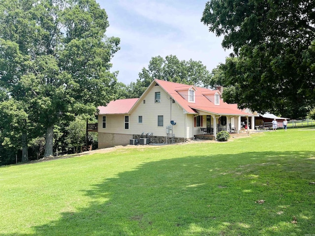 rear view of house featuring central AC unit and a yard