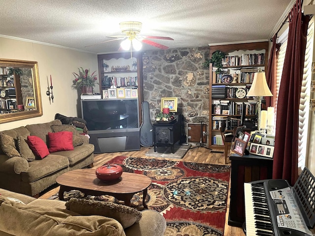 living room featuring a wood stove, a textured ceiling, ceiling fan, and light wood-type flooring