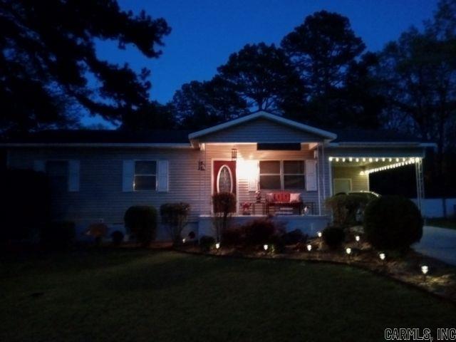 view of front of property featuring driveway, an attached carport, a porch, and a yard