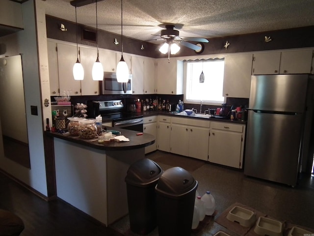 kitchen with a textured ceiling, decorative light fixtures, appliances with stainless steel finishes, kitchen peninsula, and ceiling fan