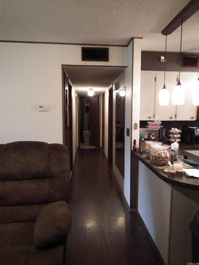 hallway with a textured ceiling and dark hardwood / wood-style flooring