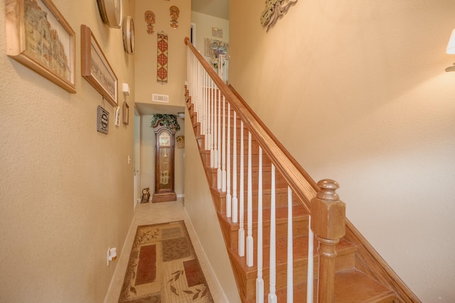 staircase with a high ceiling and tile patterned floors