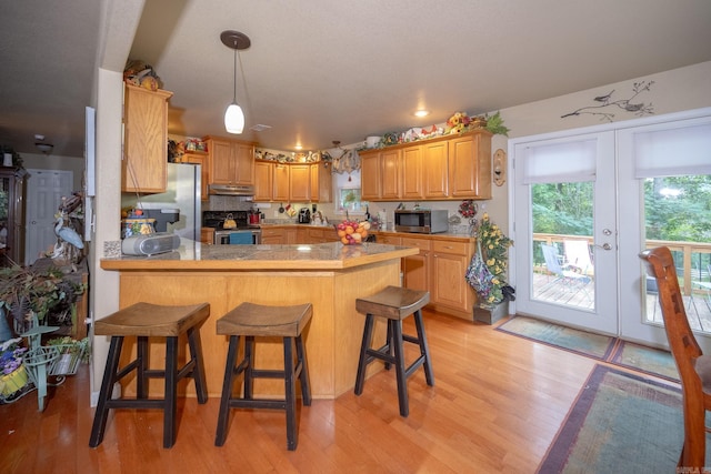 kitchen with light hardwood / wood-style floors, french doors, kitchen peninsula, a breakfast bar, and stainless steel appliances