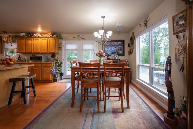 dining space with french doors, a chandelier, and light hardwood / wood-style floors