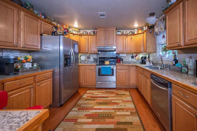 kitchen featuring light hardwood / wood-style floors, sink, a textured ceiling, and appliances with stainless steel finishes