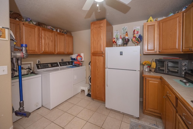 washroom with washing machine and clothes dryer, ceiling fan, a textured ceiling, and light tile patterned flooring