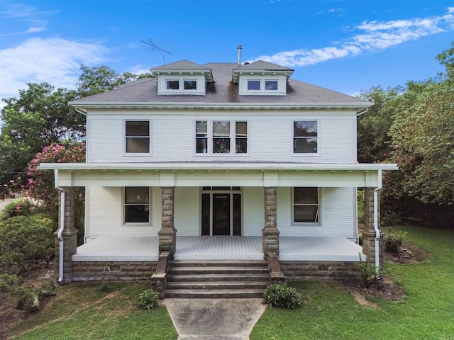 american foursquare style home featuring covered porch and a front lawn