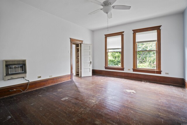 spare room with baseboards, heating unit, a ceiling fan, and hardwood / wood-style flooring