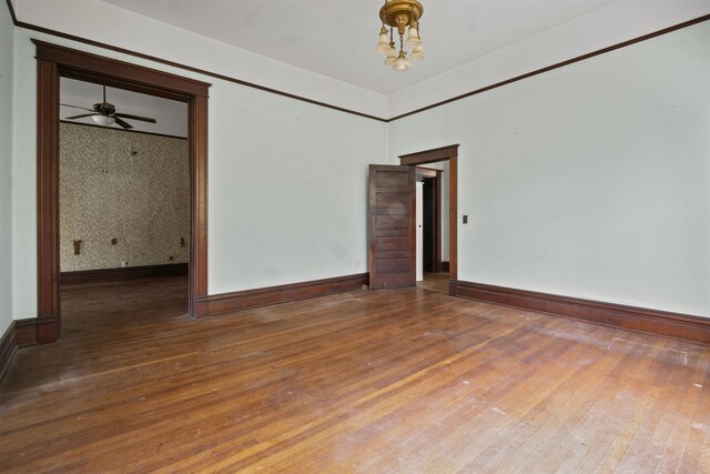 empty room with wallpapered walls, a ceiling fan, baseboards, and wood-type flooring