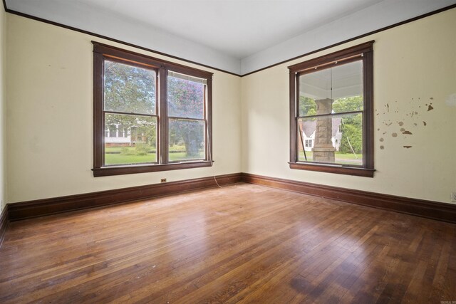 unfurnished room with baseboards and hardwood / wood-style flooring