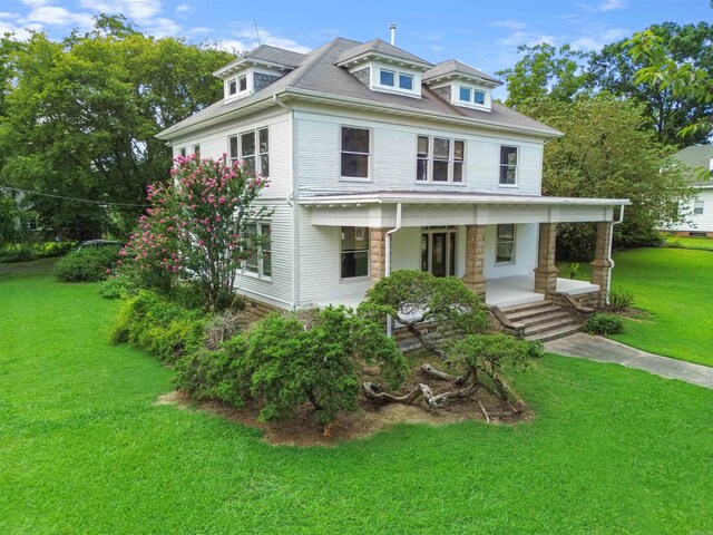 american foursquare style home with covered porch and a front yard