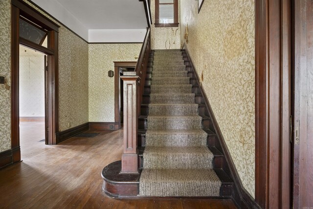 stairs featuring wallpapered walls, baseboards, and wood finished floors