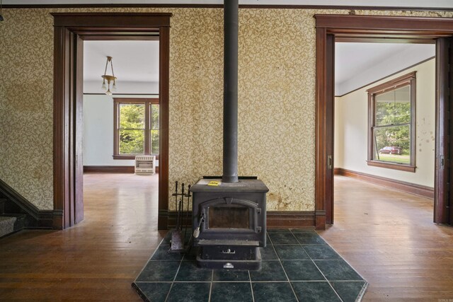 room details with wallpapered walls, a wood stove, wood finished floors, and baseboards