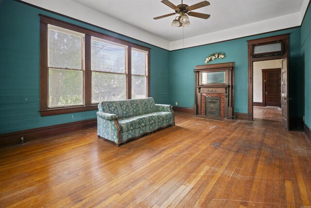 sitting room featuring a fireplace, baseboards, a ceiling fan, and wood-type flooring