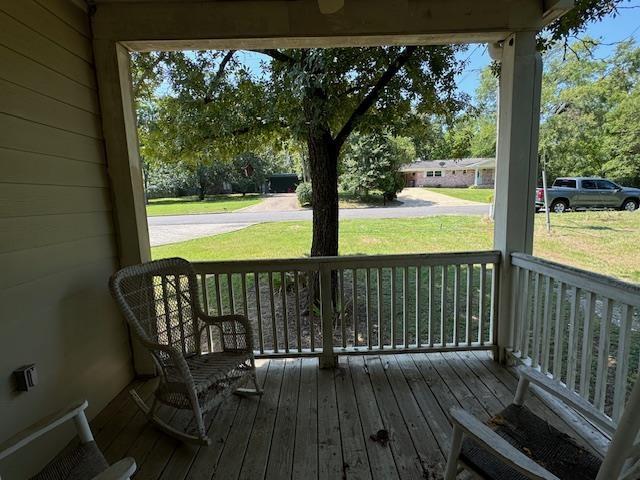 deck with a porch and a yard