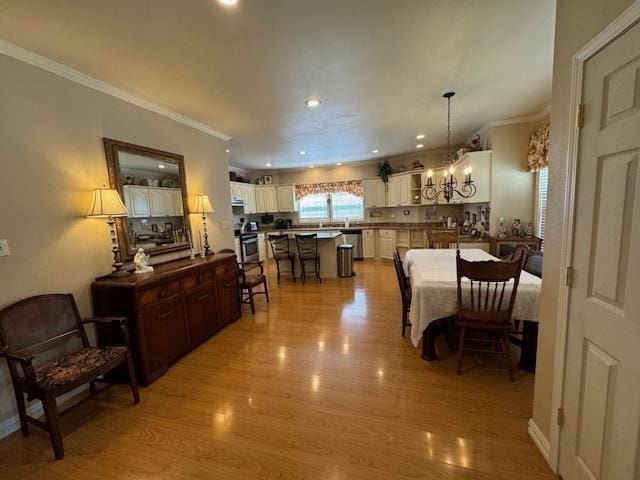 dining area with light hardwood / wood-style flooring, crown molding, and a notable chandelier