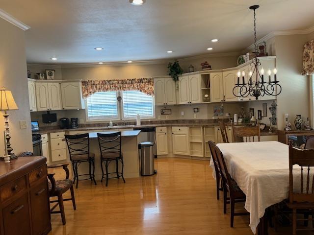 kitchen featuring light wood-type flooring, white cabinetry, pendant lighting, and a kitchen bar