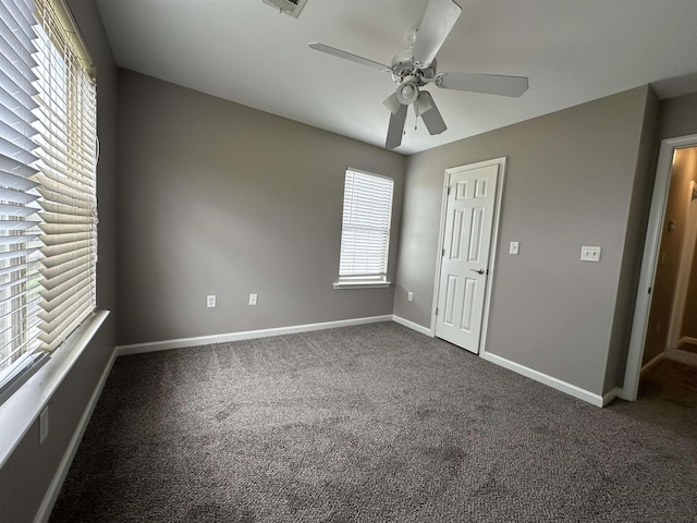 unfurnished bedroom with ceiling fan and dark colored carpet