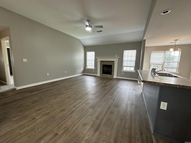 unfurnished living room featuring a healthy amount of sunlight, vaulted ceiling, dark hardwood / wood-style flooring, and sink