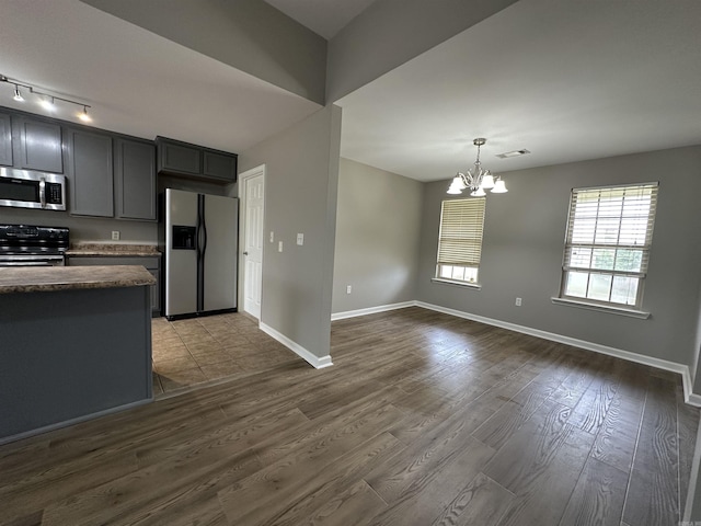 kitchen featuring an inviting chandelier, hanging light fixtures, gray cabinetry, stainless steel appliances, and dark hardwood / wood-style flooring