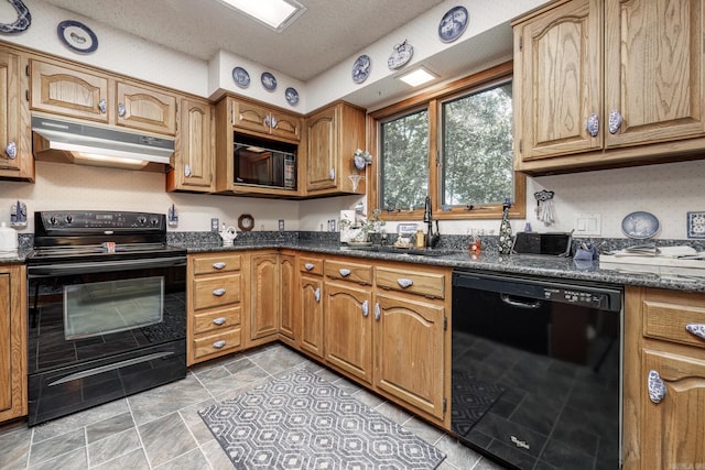 kitchen with dark stone counters, black appliances, sink, light tile patterned floors, and a textured ceiling