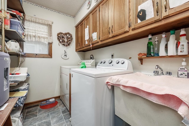 clothes washing area featuring dark tile patterned floors, washing machine and clothes dryer, sink, cabinets, and a textured ceiling