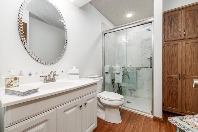 bathroom featuring vanity, hardwood / wood-style floors, an enclosed shower, toilet, and a textured ceiling