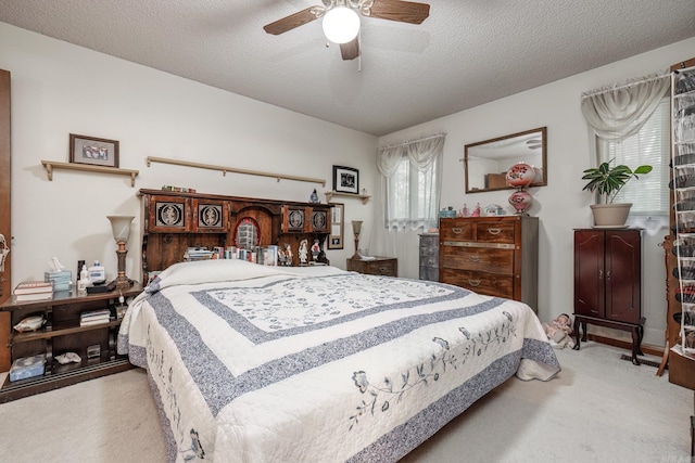 bedroom featuring light carpet, a textured ceiling, and ceiling fan