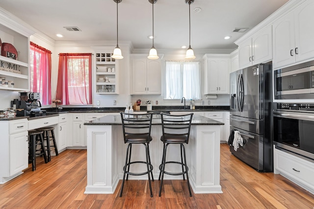 kitchen with a center island, a kitchen bar, light hardwood / wood-style floors, appliances with stainless steel finishes, and white cabinets