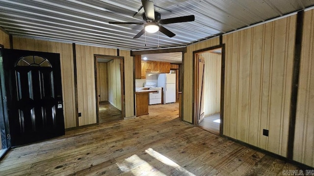 interior space with ceiling fan, wood walls, and hardwood / wood-style flooring