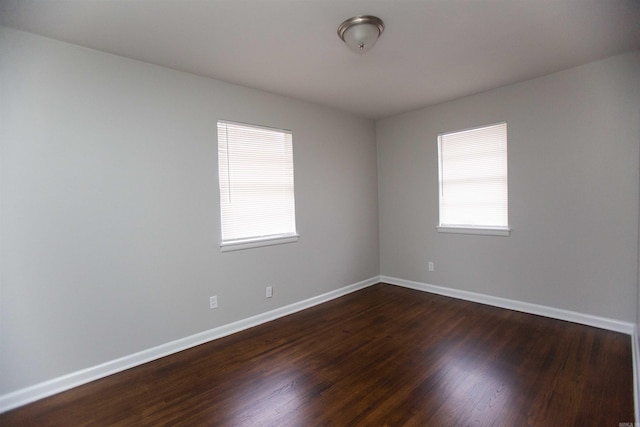 empty room featuring dark wood-type flooring and plenty of natural light