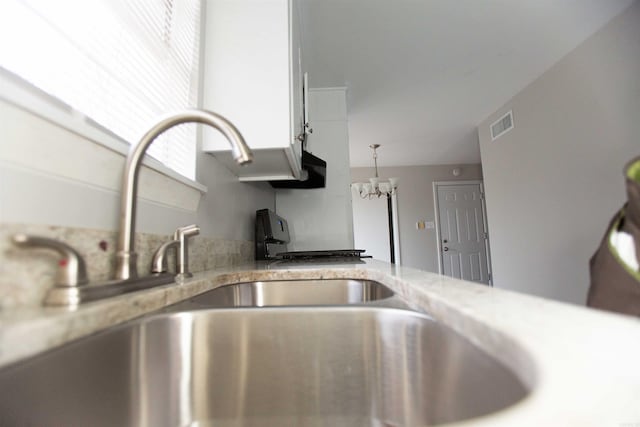 interior details with an inviting chandelier, pendant lighting, and light stone countertops