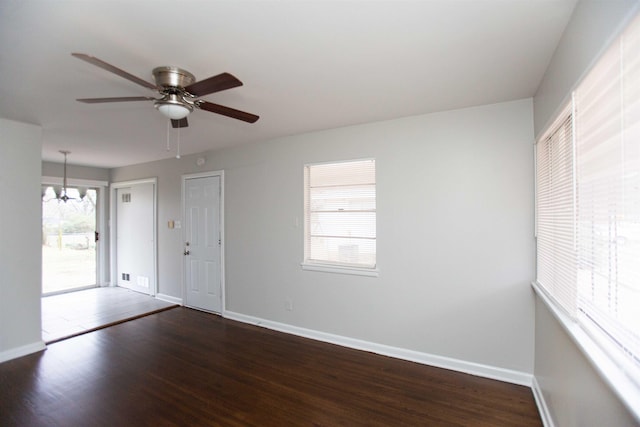 empty room with ceiling fan with notable chandelier and dark hardwood / wood-style floors