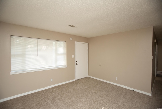 unfurnished room featuring light carpet and a textured ceiling