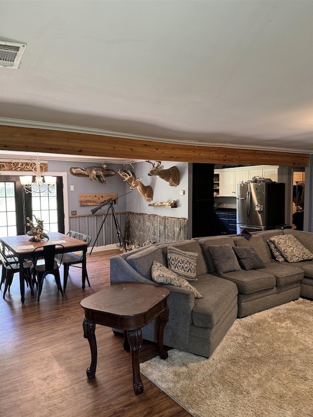 living room with dark wood-type flooring, a notable chandelier, and ornamental molding